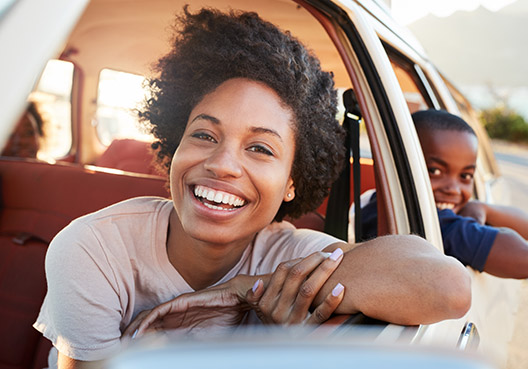 woman and child looking out the window of their car with their windows rolled down