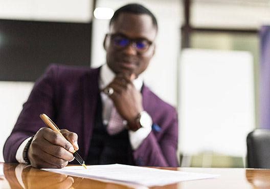 A professional in a purple suit sitting at his desk taking notes