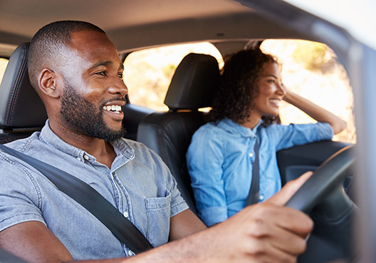 couple sitting in the car smiling and the man is driving