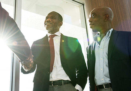 A customer shakes hands with an Old Mutual Rwanda staff member and his colleague after they discussed a loan.