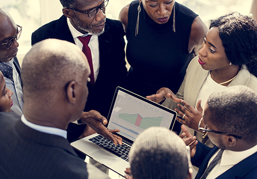 people huddled together looking at a laptop
