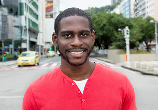 young guy in red jersey on the street smiling at the camera
